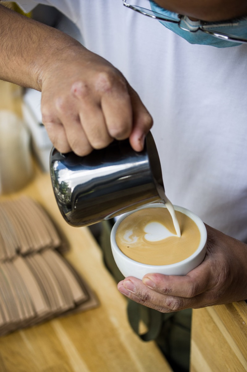 Barista pouring latte art at Café Obrkof